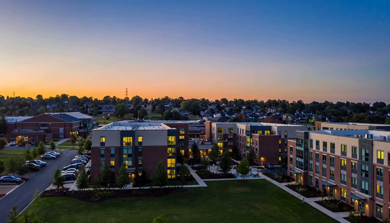 Student housing community at dusk, seen from the air as the windows light